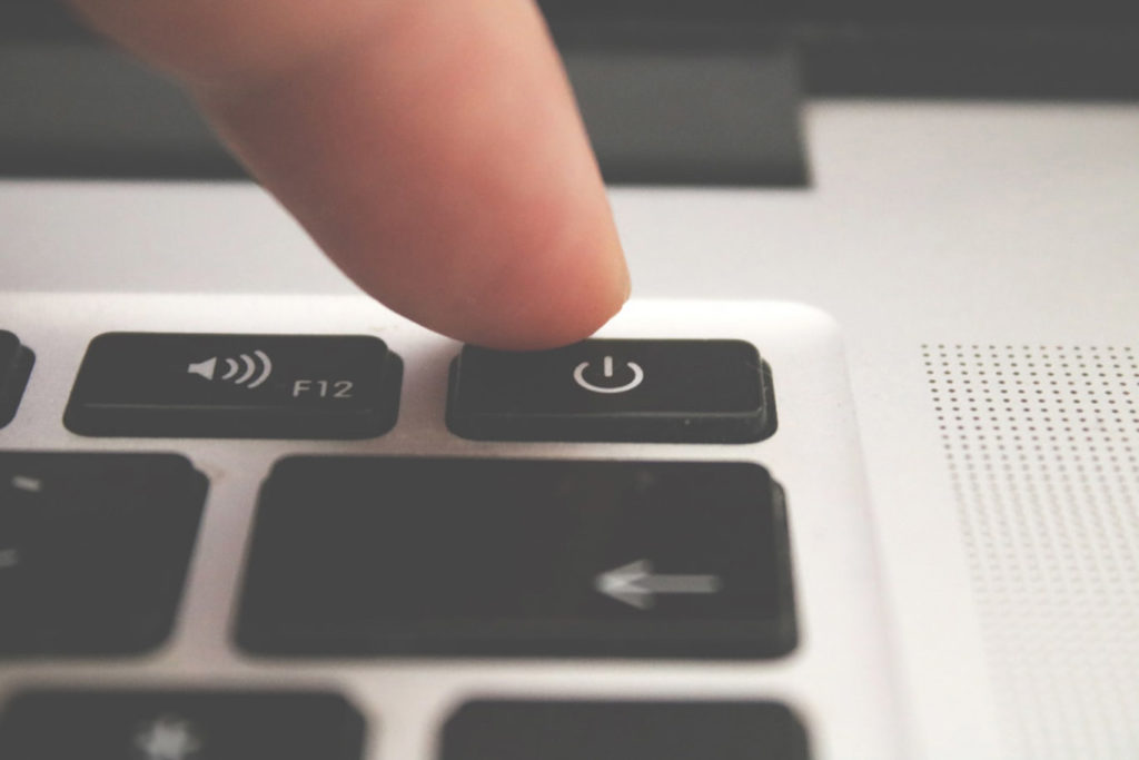 Laptop keyboard with a finger hovering over the power button