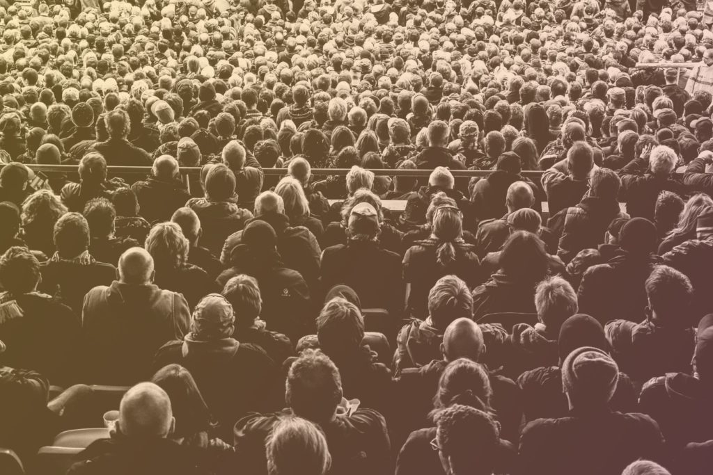 black and white photo of a crowd of people sat in a stadium