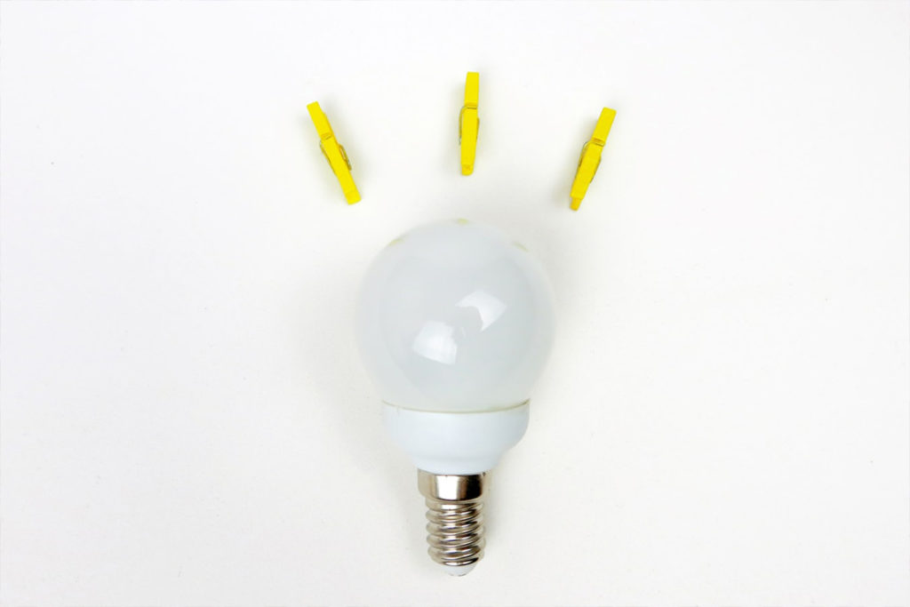 A lightbulb with yellow coloured pegs coming off it to show it being switched on